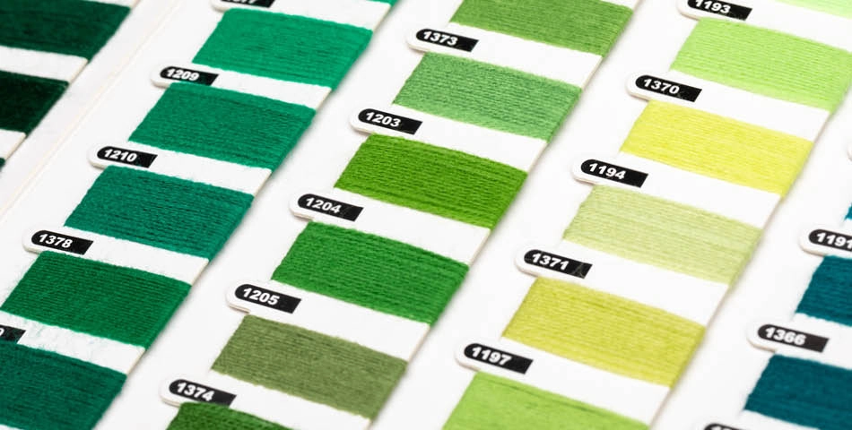 Close-up of a color chart displaying various shades of green thread samples, each labeled with a unique identification number.