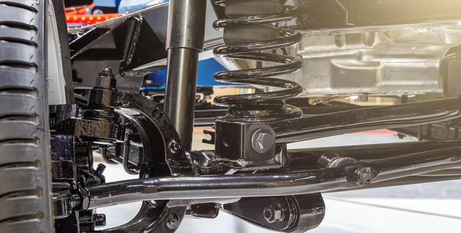 Close-up view of a vehicle's suspension system, showing the coil spring, shock absorber, and tire.