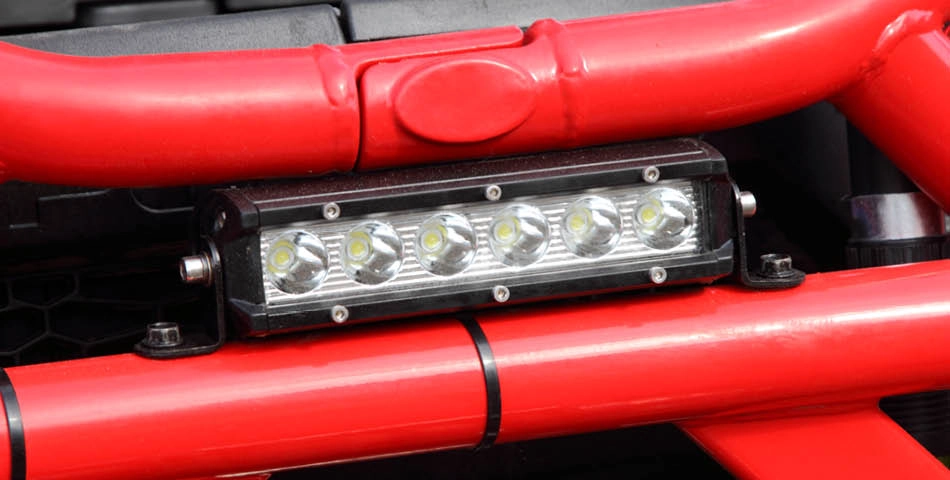 A close-up of a rectangular LED light bar mounted on red metal tubing, likely part of a vehicle's bumper or frame.