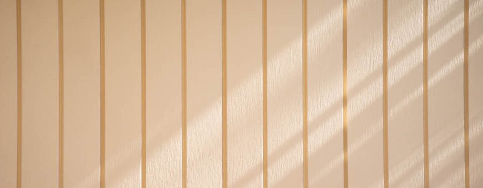 Light beige vertical wooden panels with diagonal shadows cast across the surface.