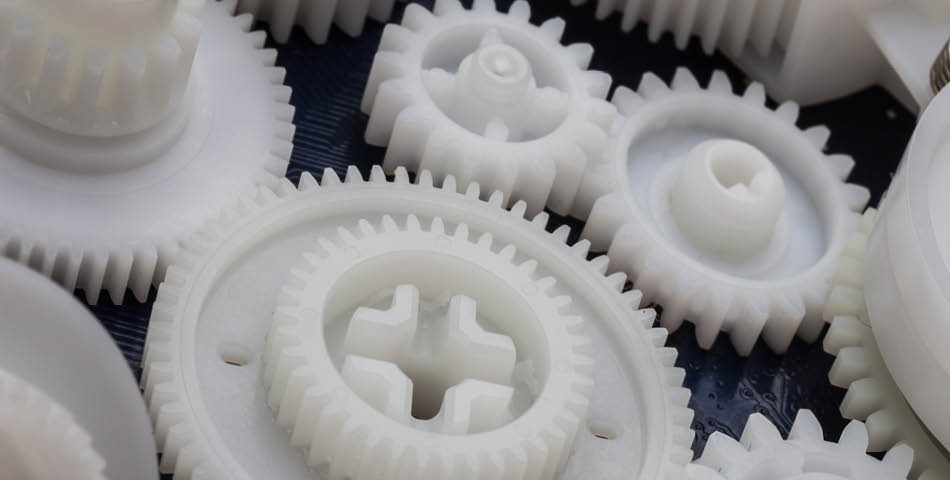Close-up view of several interlocking white plastic gears of various sizes.