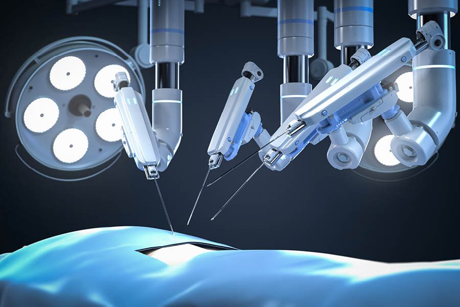 Robotic surgical arms perform a medical procedure on a patient under bright operating room lights.
