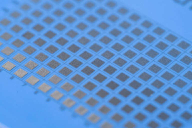 Close-up of a blue grid with patterned squares, possibly representing a microchip or semiconductor wafer surface.