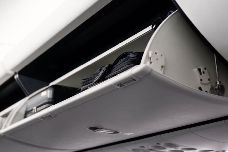 Open airplane overhead compartment with black suitcases stored inside. The label "28 A" is visible on the compartment.