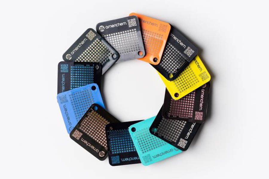 Twelve rectangular plastic color sample chips arranged in a circle, each labeled "Americhem" with a grid pattern and a QR code, in various colors including black, gray, blue, and yellow.