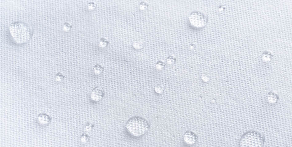 Water droplets scattered on a white, textured fabric surface.