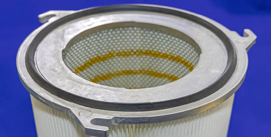 Close-up of a cylindrical industrial air filter with a metal frame and pleated paper material, set against a blue background.