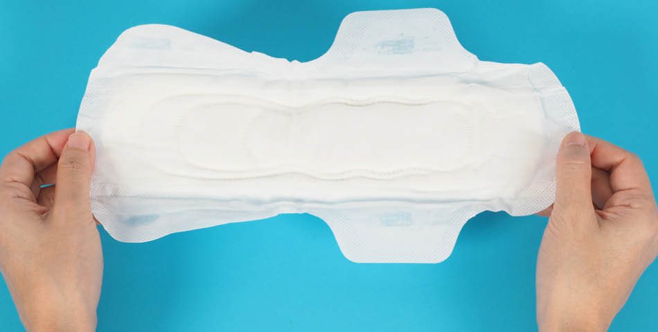 Two hands holding an unused sanitary pad against a blue background.